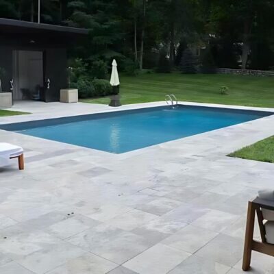 a beautiful pool area with elegance travertine pavers in various natural colors and textures, creating a luxurious outdoor space.