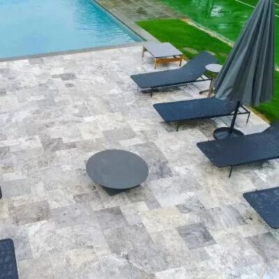 a beautiful travertine deck surrounds a swimming pool, showcasing an environmentally friendly and sustainable choice for outdoor decking material.