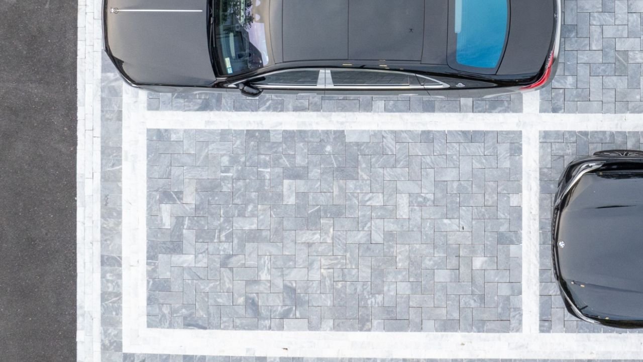 Driveway paved with long rectangular stone pavers in a directional layout