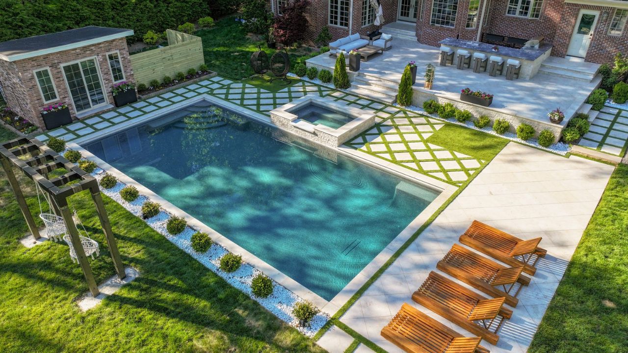 Luxury outdoor living area featuring natural stone patio, pool coping, walkways, and outdoor kitchen