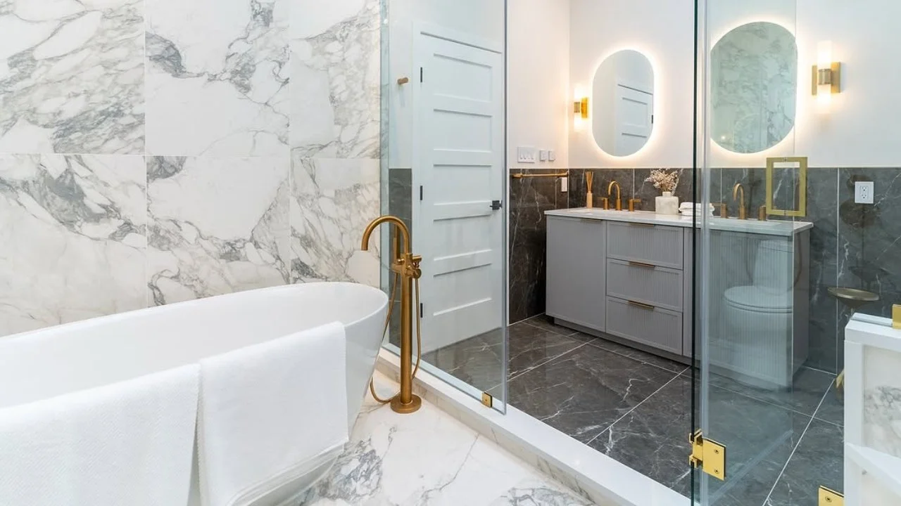 Modern bathroom with marble-look porcelain wall tiles and dark large-format floor tiles by NT Pavers